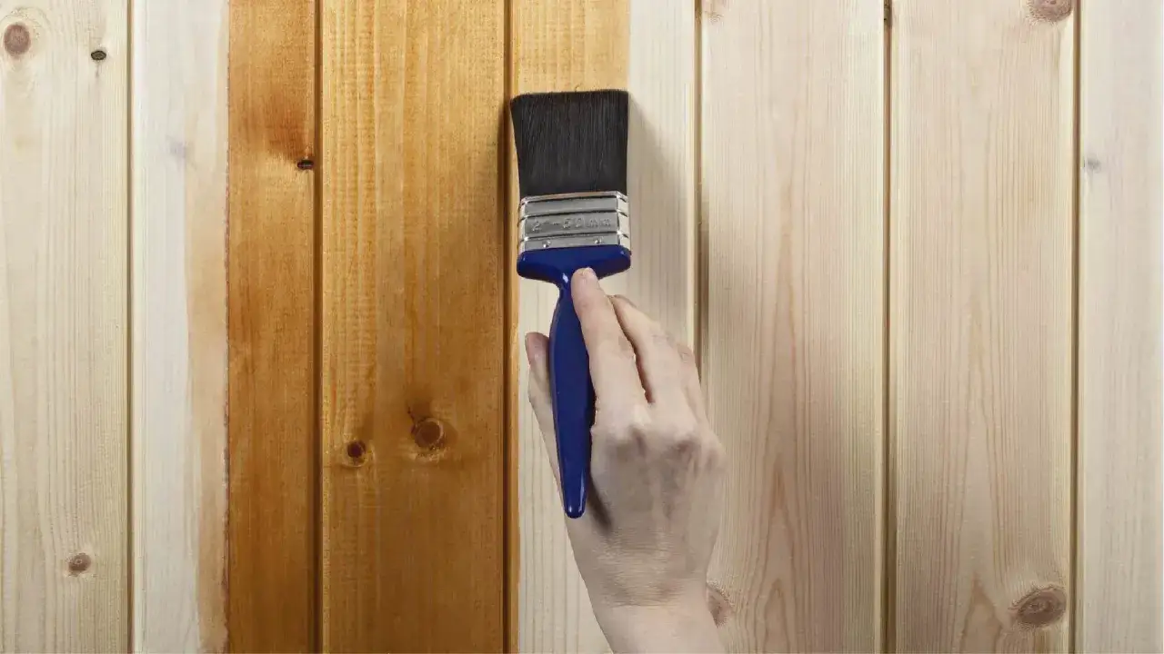 Mano aplicando barniz a madera, mostrando el antes y el después. El proceso de barnizar madera protege y embellece.