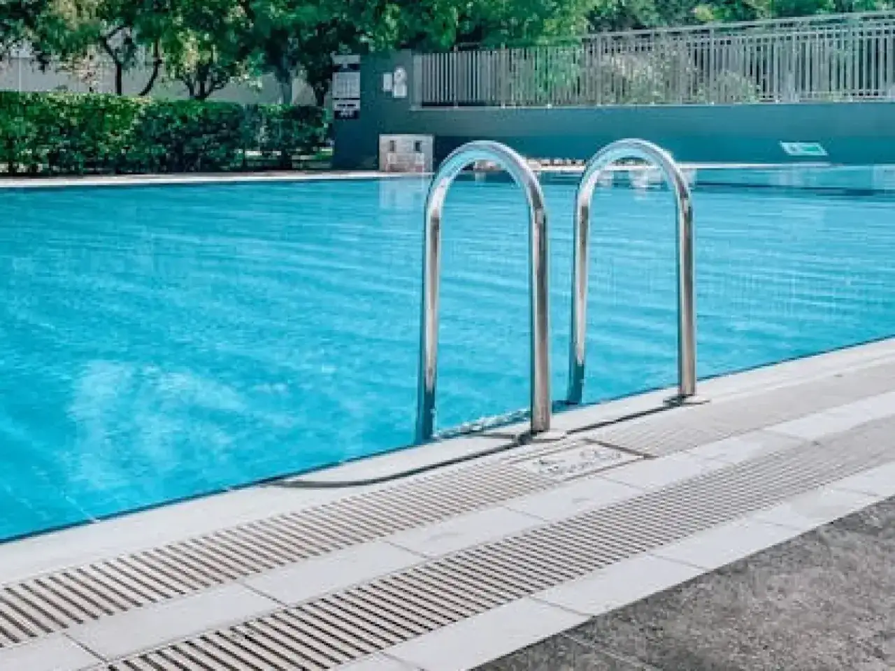Escaleras cromadas en una piscina de agua azul. Se puede echar cloro a una piscina de sal para mantenerla limpia.