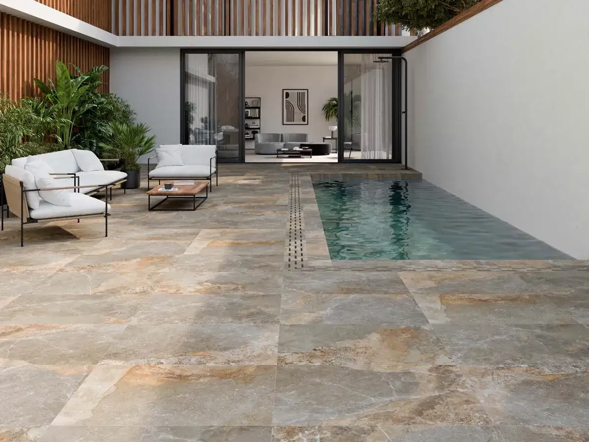 Patio moderno con piscina y sof&aacute;s blancos. El suelo de baldosas imita piedra natural, ideal para distintos tipos de z&oacute;calos para paredes exteriores.