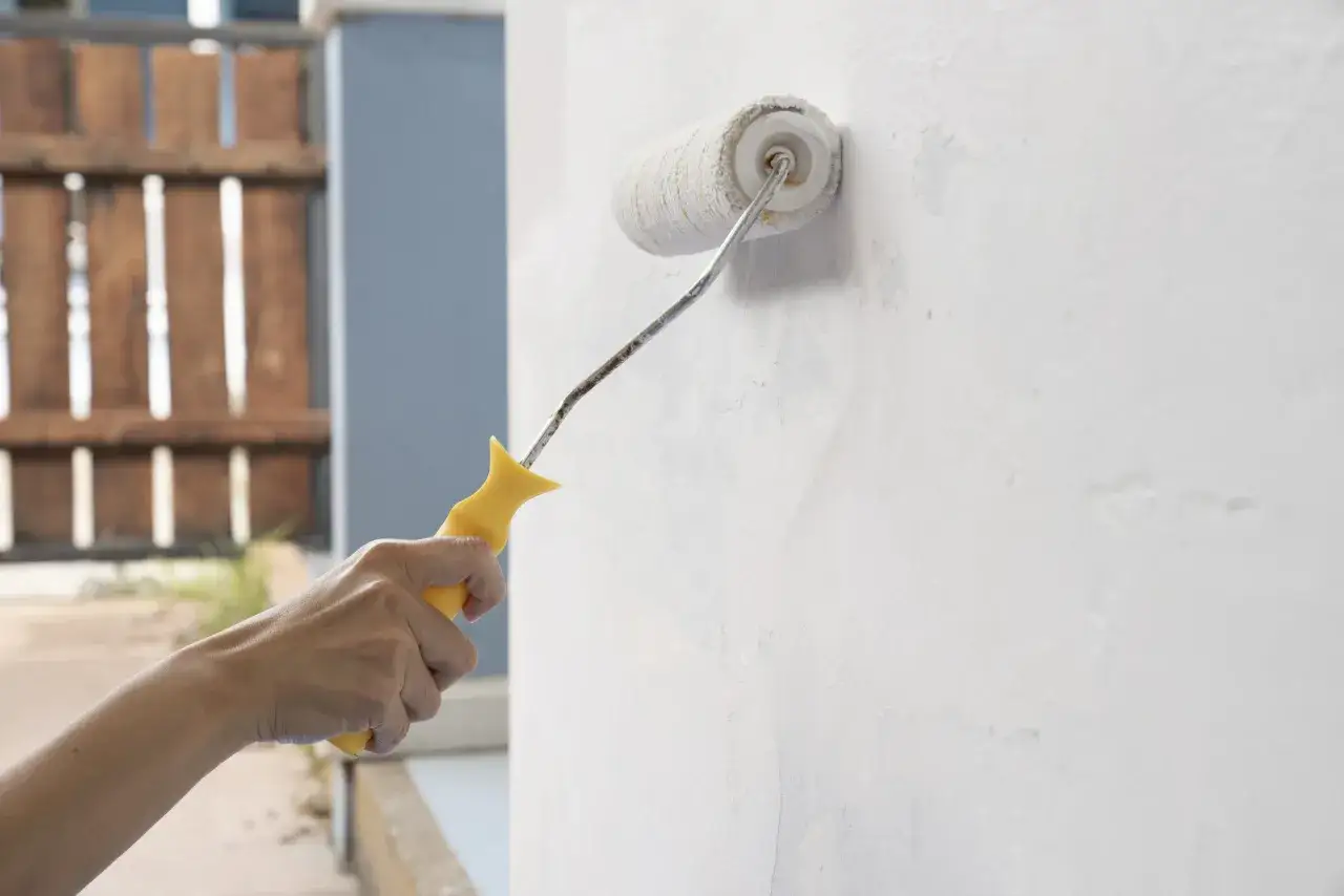 Mano aplica imprimación blanca a pared con rodillo. Preparando la superficie para pintar.