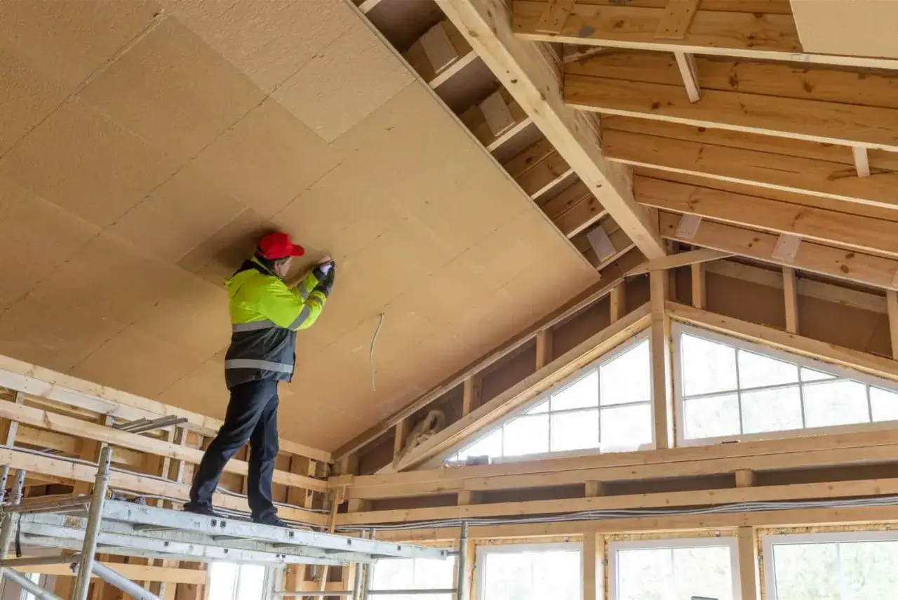 Trabajador instala paneles aislantes en el techo de una casa en construcción. Proceso para como aislar una casa ya construida.