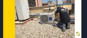 Técnico realizando mantenimiento de aire acondicionado en una azotea. Se ve una unidad Haier y otras unidades de climatización.