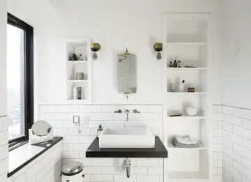 Modern bathroom with a white rectangular lavabo sobre mueble de madera oscura. Estanterías blancas a los lados.