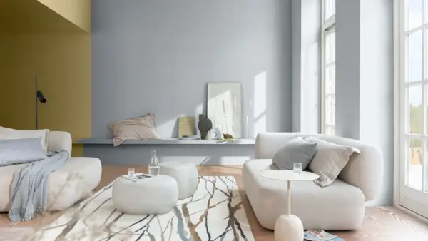 Salón moderno con sofás blancos, alfombra de ramas y paredes en pintura al agua gris y ocre.