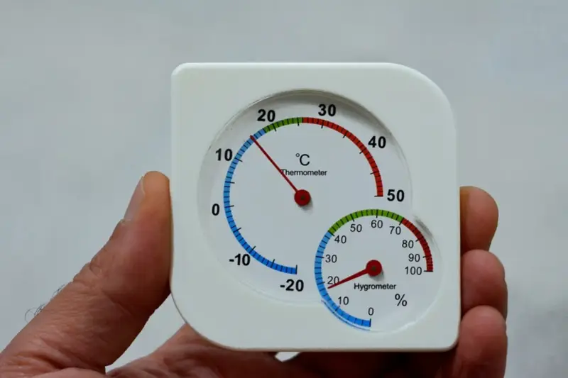 Termómetro y higrómetro en mano, mostrando cómo medir la humedad en casa.